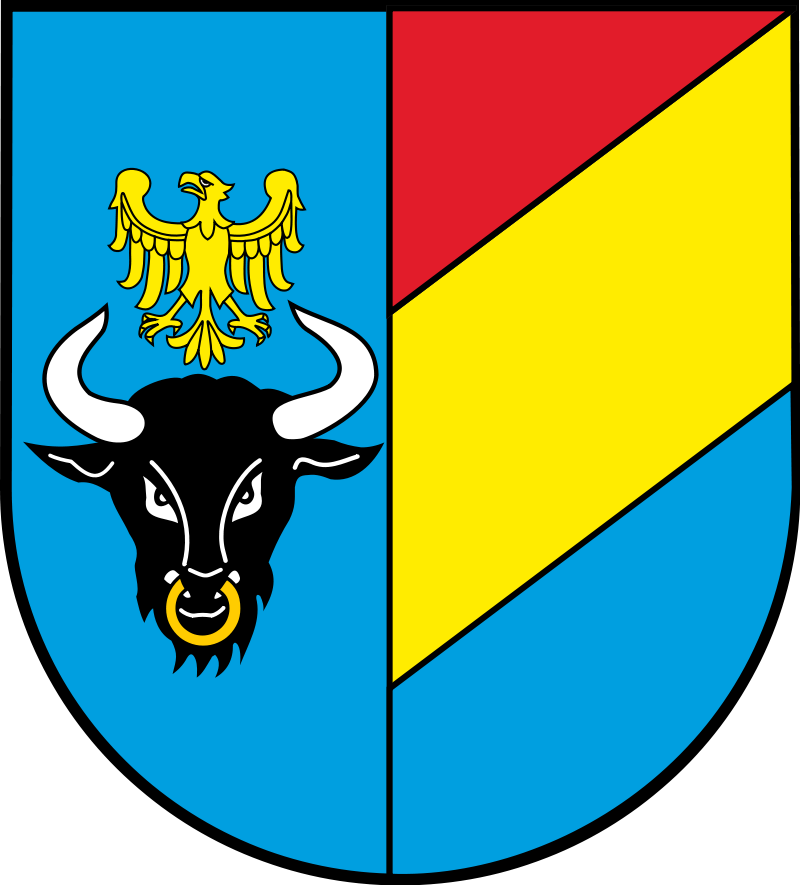 Herb powiatu żywieckiego: po prawej złoty orzeł śląski nad czarną głową żubra, po lewej trzy skośne pasy – czerwony, żółty i błękitny.